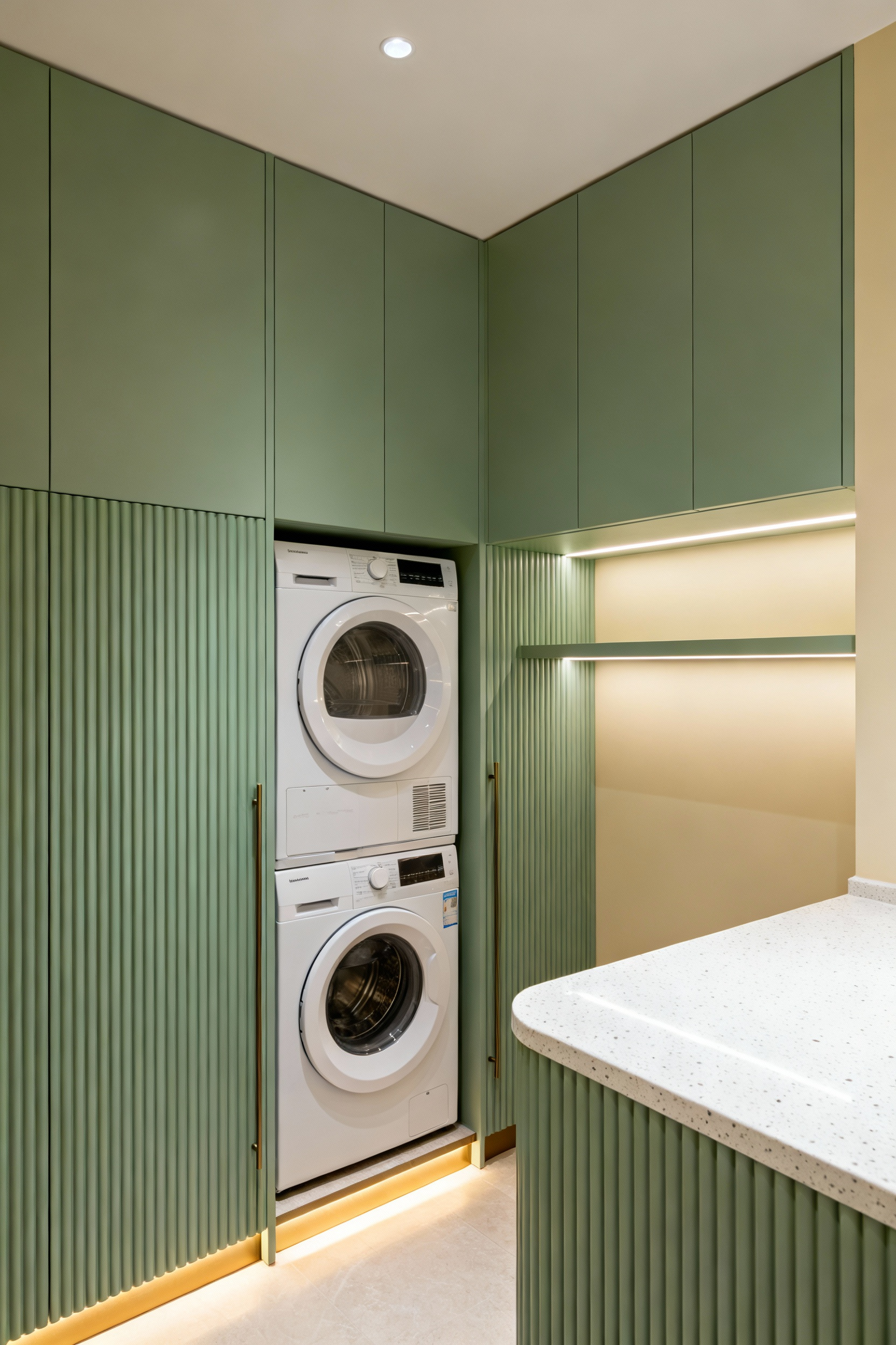 Sophisticated hotel-inspired laundry room with integrated sage green paneling concealing appliances, a cohesive color palette, and luxurious utility space design.
