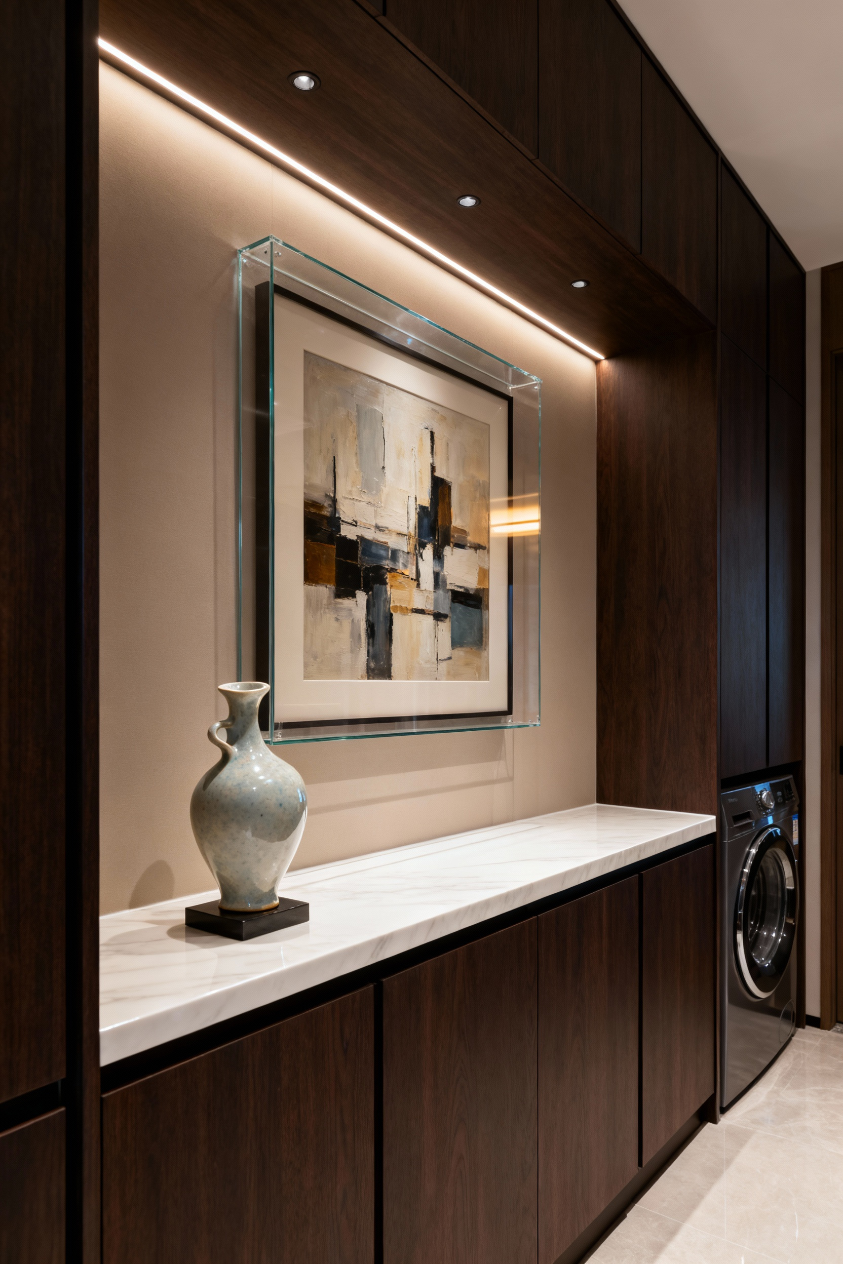 A sophisticated luxury laundry room featuring a wall with framed abstract artwork, an elegant ceramic sculpture on a shelf, and dark wood cabinetry under soft lighting, creating a high-end, gallery-like aesthetic.