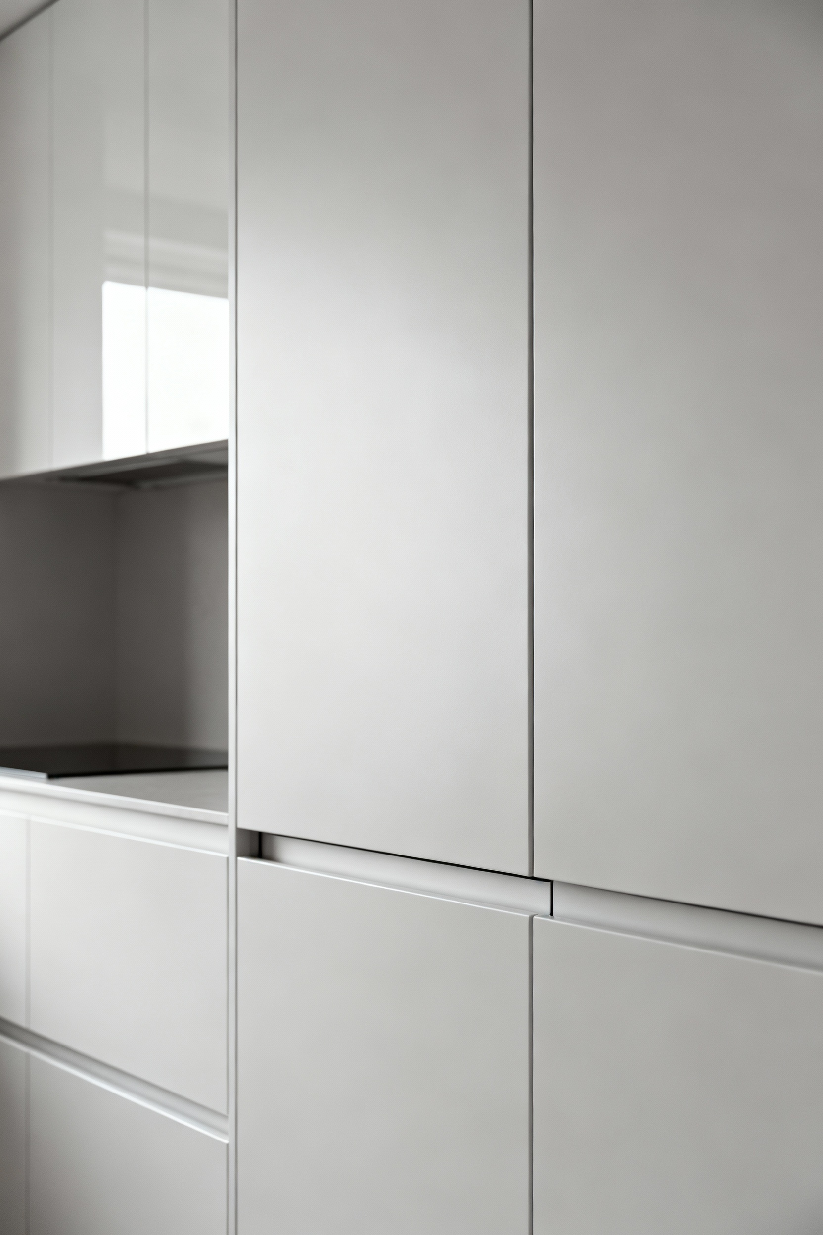 Portrait view of modern handleless kitchen cabinets with push-open mechanisms, emphasizing sleek, minimalist design and clean aesthetics.